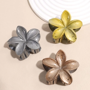 Close-up of matte lily flower hair claws with artistic ink splatter texture in three colors