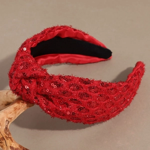 Close-up of red sequin knotted headband with woven mesh texture on a wood display