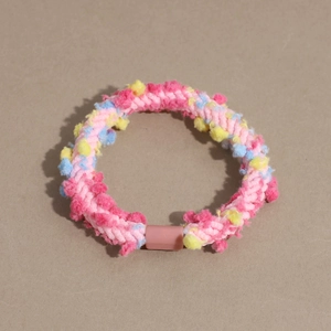 Detailed macro view of colorful woven plush hair tie with vibrant dopamine-style pom-poms