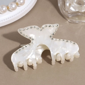 Close-up of elegant cream white hair claw clip with mother of pearl luster and rhinestones
