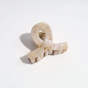 Detail of matte marble hair claw clip with golden metal spring and multi-tooth grip