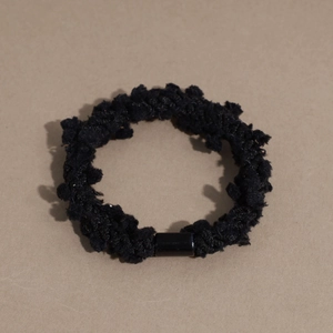 Macro shot of black textured bobble hair tie with sleek rectangular closure clip