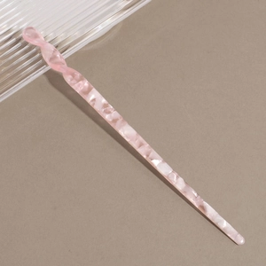 Detailed macro shot of a pink marble acetate hair stick with a twisted spiral top design