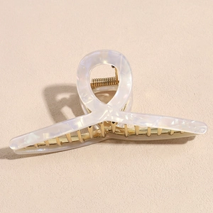 Macro detail of large 12cm hair claw clip with pearl white finish and golden alloy metal teeth