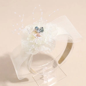 Detail of white chiffon flower headband with mesh bow, pearls and colorful crystals