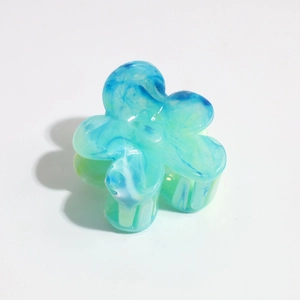 Detailed close-up of flower shaped hair claw with blue-green marble texture finish