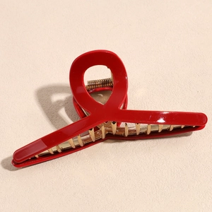 Macro detail of red acrylic metal hair claw clip with golden teeth and strong spring