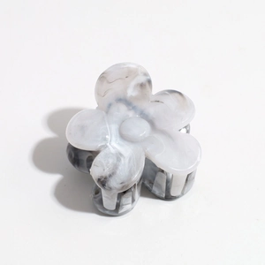 Detailed close-up of a floral hair claw clip featuring grey marble texture and matte finish