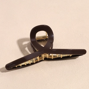 Detail of a 12cm dark brown glossy hair claw clip with golden metal teeth and spring