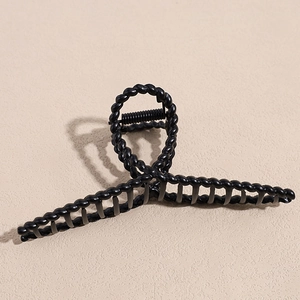 Detail view of a matte black twisted hair claw clip with strong metal spring