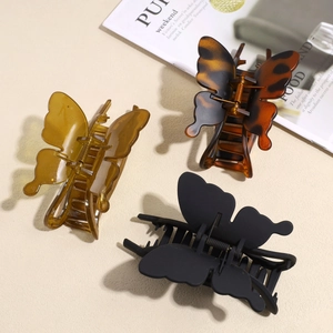 Three elegant butterfly hair claws in matte black, tortoiseshell, and amber finishes