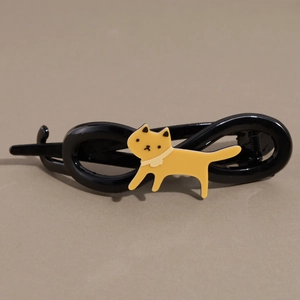 Dettaglio del fermaglio nero con motivo a gatto giallo e design a torsione