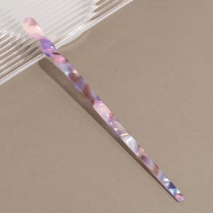 Macro detail of elegant pink marble acetate hair stick with glossy twisted texture