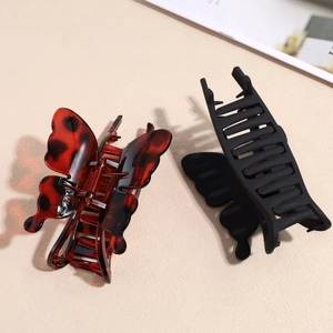 Detail of butterfly hair claw clips in red tortoiseshell and matte black finish