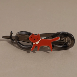 Dettaglio del fermaglio per capelli in resina grigio scuro con ciondolo a gatto rosso
