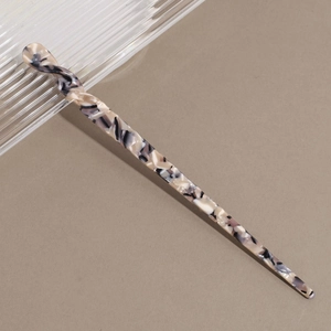 Detail of acetate hair stick showing elegant marble ink texture and twisted spiral top