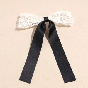Detail von eleganter weißer Spitzenblume und schwarzer Seidenschleife Haarclip Textur