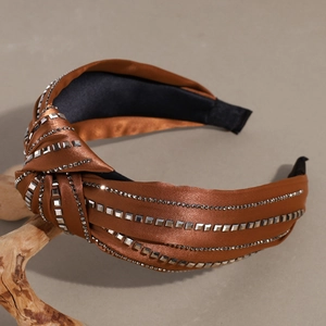 Detail of a brown satin knotted headband featuring silver studs and sparkling rhinestones