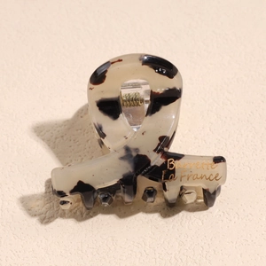 Macro di mini pinza per capelli tartarugata con dettaglio a molla in metallo dorato