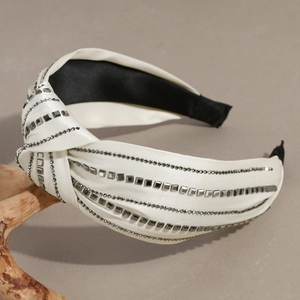 Detailed view of cream silk knot headband with sparkling grey rhinestones and metal studs