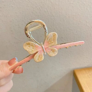 Detail of a large golden butterfly hair claw clip with pink and beige resin wing texture