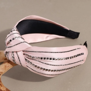 Detail of pink satin knotted headband with shiny rhinestone rows and knotted design