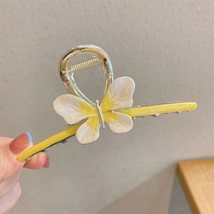 Detailed close-up of a butterfly hair claw clip with yellow and white wings in hand