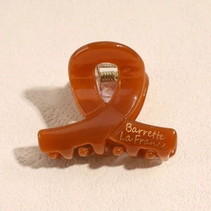 Dettaglio di un mollettone marrone in resina con incisione dorata Barrette La France