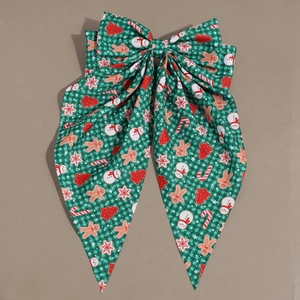 Detail view of large Christmas bow hair clip with gingerbread man and snowman prints