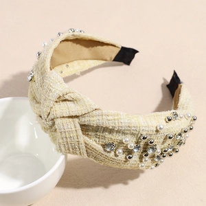 Detail of tweed headband with pearls and rhinestones on a minimalist beige background
