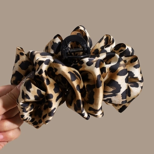 Detail of leopard print claw clip showing pleated fabric texture and patterned fabric finish