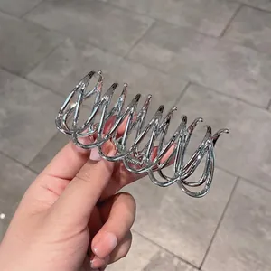 Haarklammer aus Silbermetall mit hohlem Kreuzdesign für dickes Haar in der Hand