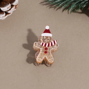 Close-up of gingerbread man hair clip with gold sequins and festive Christmas scene background