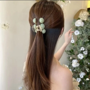 Detail view of light green pearl shark hair clip styled in elegant half-up hairstyle