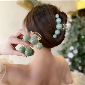 Detail showing elegant light green faux pearl hair claw clip set on a woman's hair