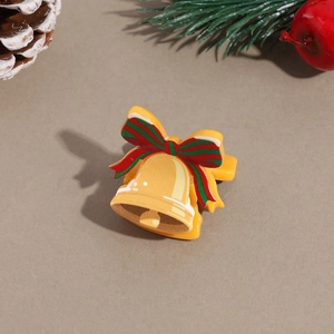 Close-up of a festive golden bell hair claw with a red and green striped ribbon bow