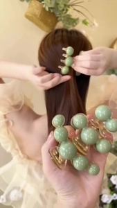 Detail of light green pearl hair claw clip showing spring mechanism and hair styling look