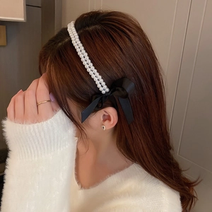 Elegant double-row pearl headband with a black silk bow, displayed on a female model