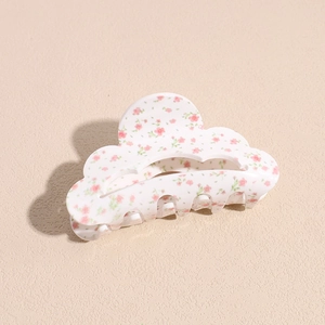 Vue détaillée de la pince à cheveux en acrylique avec motifs floraux roses sur fond blanc