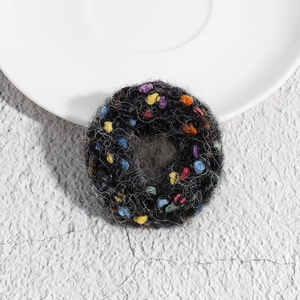 Close-up of soft black knitted hair tie with vibrant colorful polka dot accents on stone