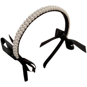 Elegant headband with double-row white pearls and black satin side bows on white background