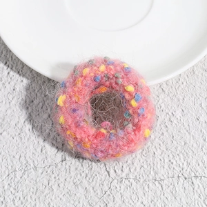 Detail of pink plush polka dot hair tie with colorful pom-poms on a white plate