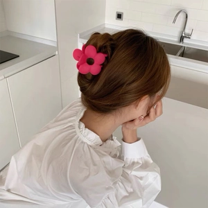 Macro view of matte rose red flower hair claw clip worn in a stylish updo on back of head