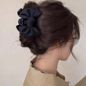 Elegant black satin bow hair claw clip for women shown on a model's back hairstyle
