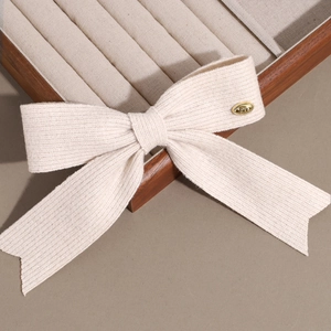 Texture détaillée du nœud en tricot beige avec une plaque en métal dorée LOVE