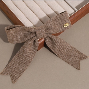 Détail d'un nœud papillon en tricot marron avec un charme doré gravé Love pour les cheveux