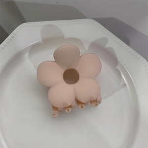 Macro view of a matte dusty pink flower hair claw clip with a hollow five-petal design