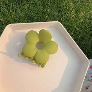 Close-up of avocado green flower hair claw clip with matte finish on white tray