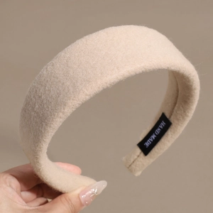 Détail d'un bandeau en laine crème avec étiquette HAND MADE noire et texture tissée