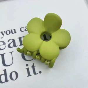 Matte lime green flower hair claw clip for women displayed on aesthetic paper background